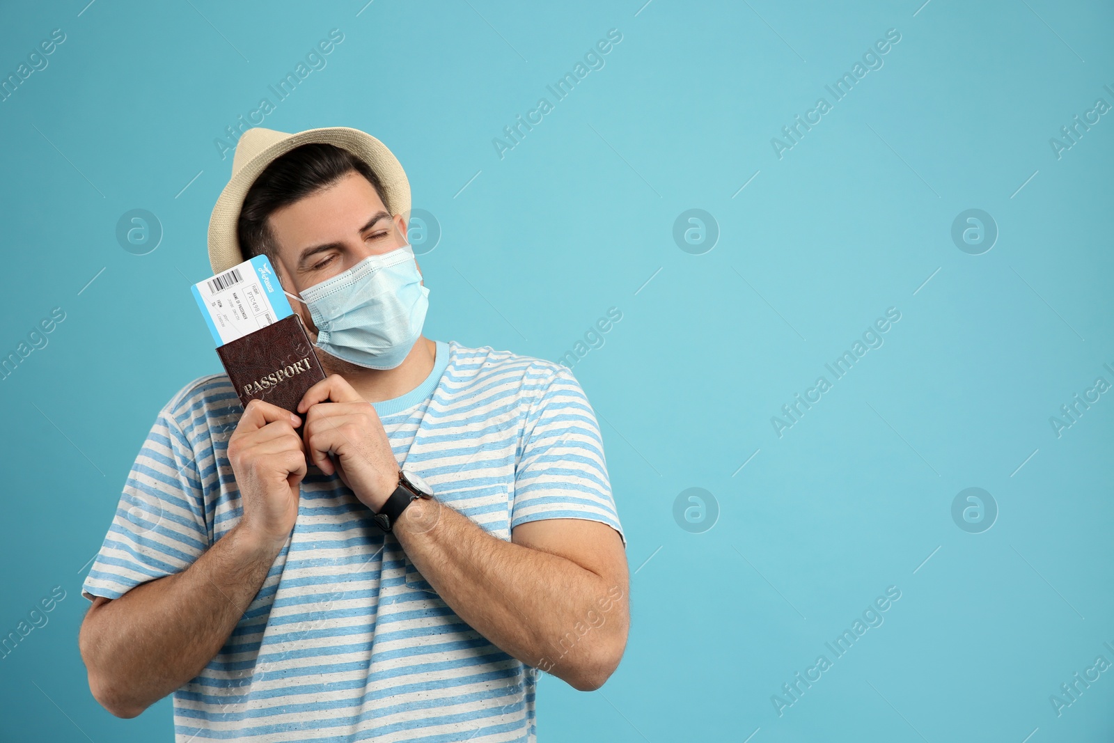 Photo of Male tourist in protective mask holding passport with ticket on turquoise background, space for text