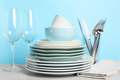 Beautiful ceramic dishware, glasses and cutlery on light grey table
