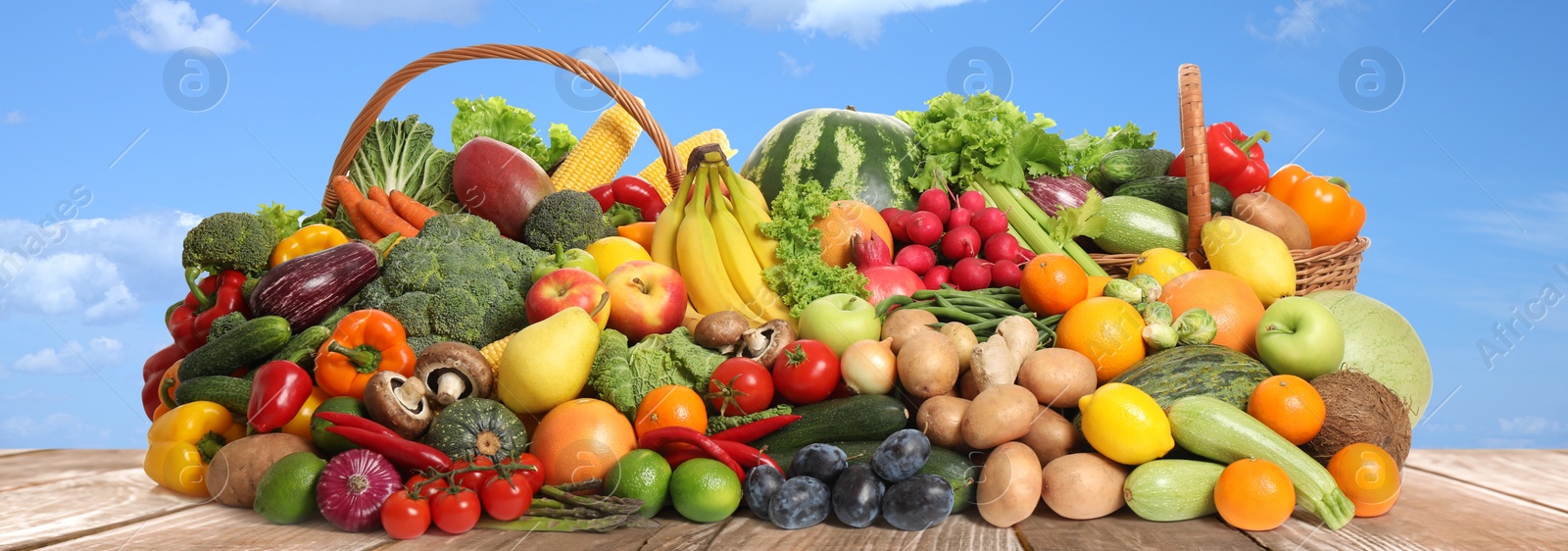 Image of Assortment of fresh organic fruits and vegetables on wooden table outdoors. Banner design