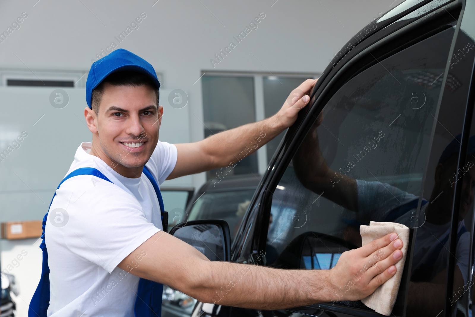 Photo of Worker washing tinted car window in workshop