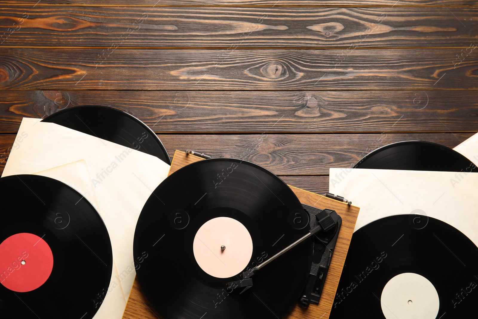 Photo of Vintage vinyl records and turntable on wooden background, flat lay. Space for text
