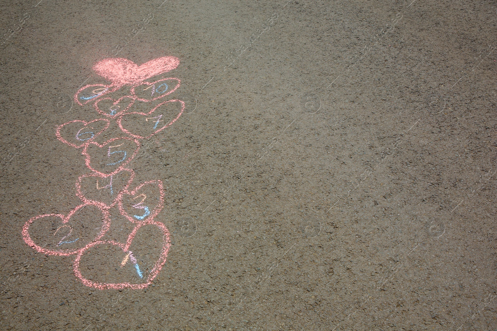 Photo of Hopscotch drawn with colorful chalk on asphalt outdoors. Space for text