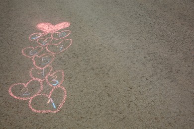 Hopscotch drawn with colorful chalk on asphalt outdoors. Space for text