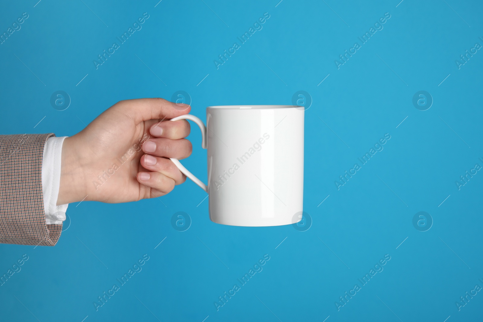 Photo of Woman holding white mug on light blue background, closeup. Space for text