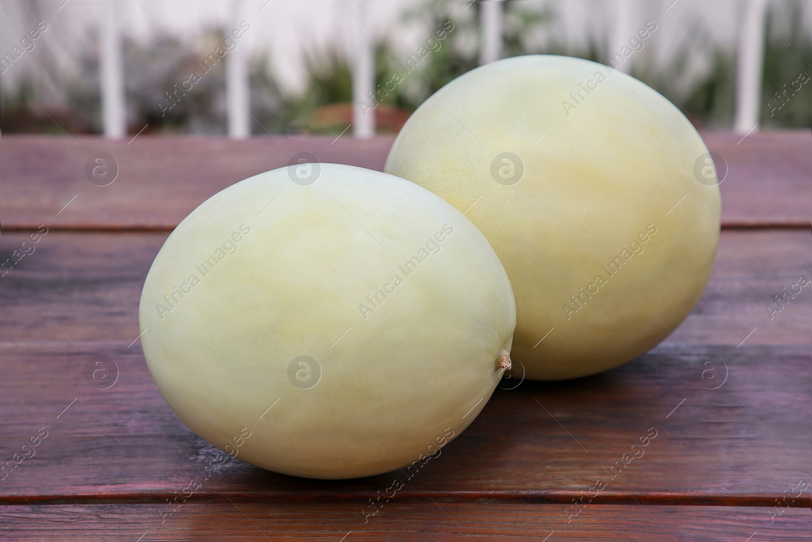 Photo of Whole fresh ripe melons on wooden table outdoors