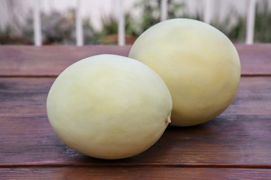 Photo of Whole fresh ripe melons on wooden table outdoors