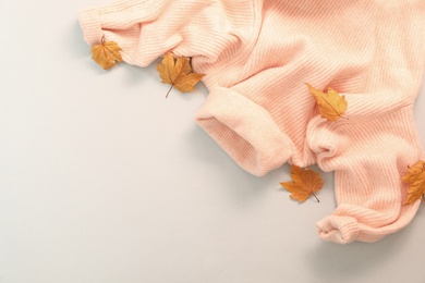 Photo of Pink warm sweater and dry leaves on white background, top view. Autumn season