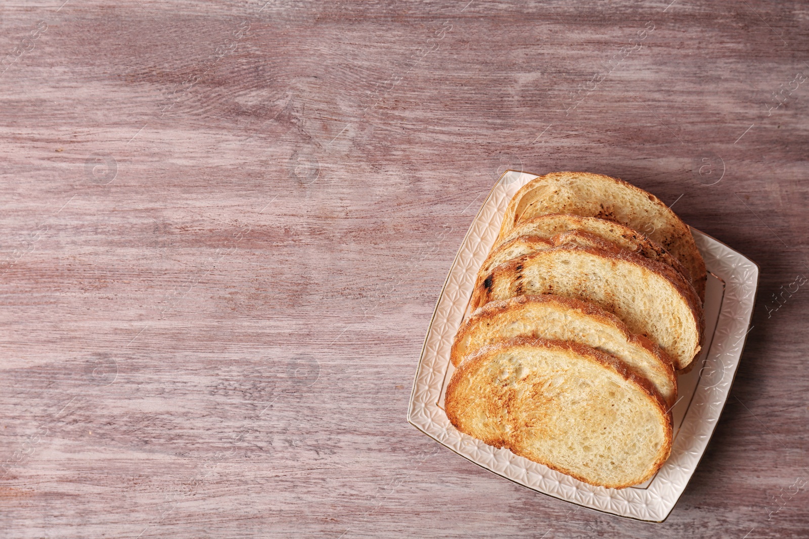 Photo of Plate with toasted bread on wooden background, top view