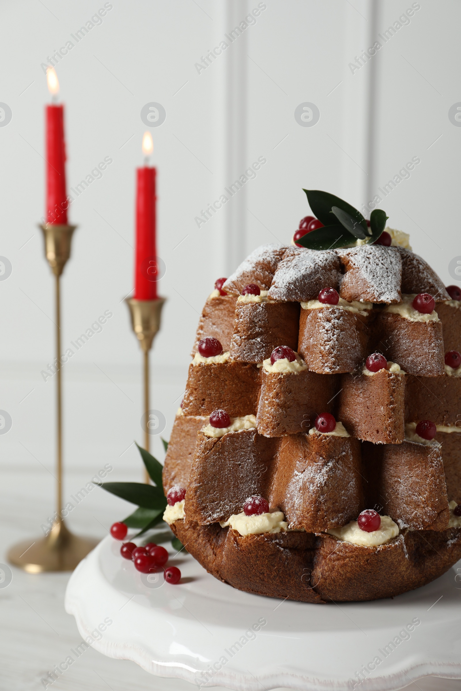 Photo of Delicious Pandoro Christmas tree cake with powdered sugar and berries near festive decor on white table