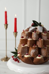 Delicious Pandoro Christmas tree cake with powdered sugar and berries near festive decor on white table