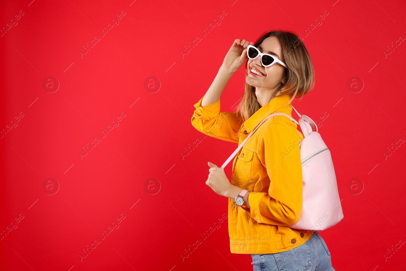 Photo of Happy woman with backpack on red background. Space for text