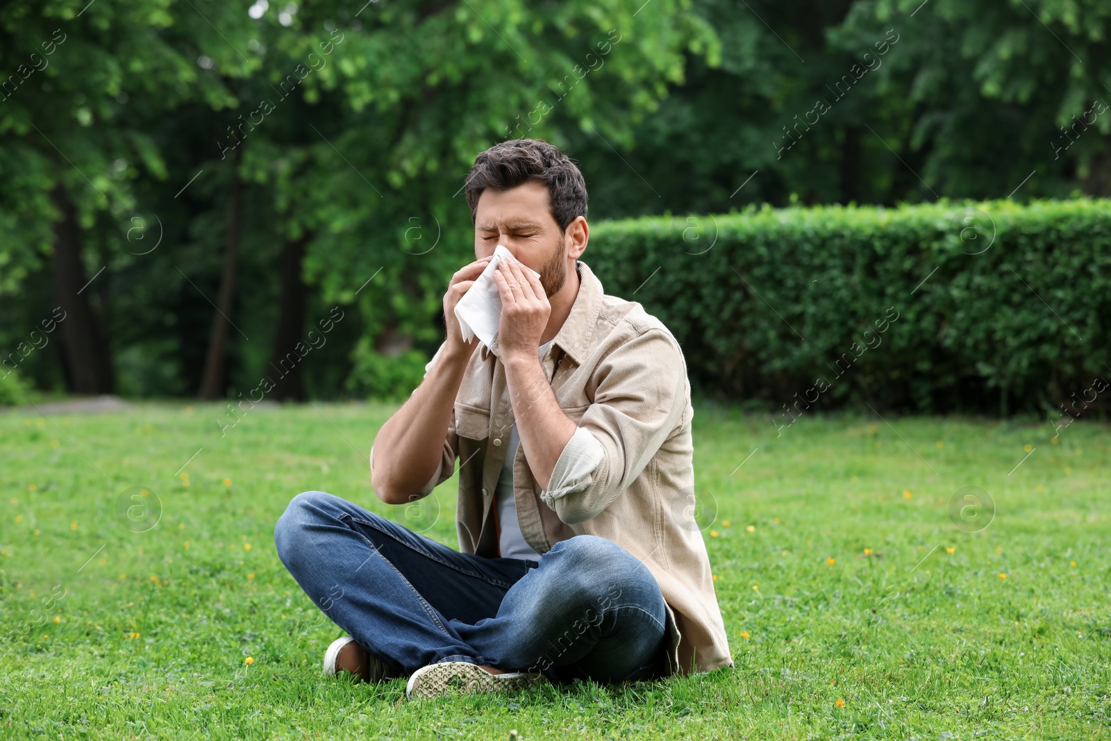 Photo of Man suffering from seasonal spring allergy on green grass in park