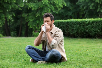 Man suffering from seasonal spring allergy on green grass in park