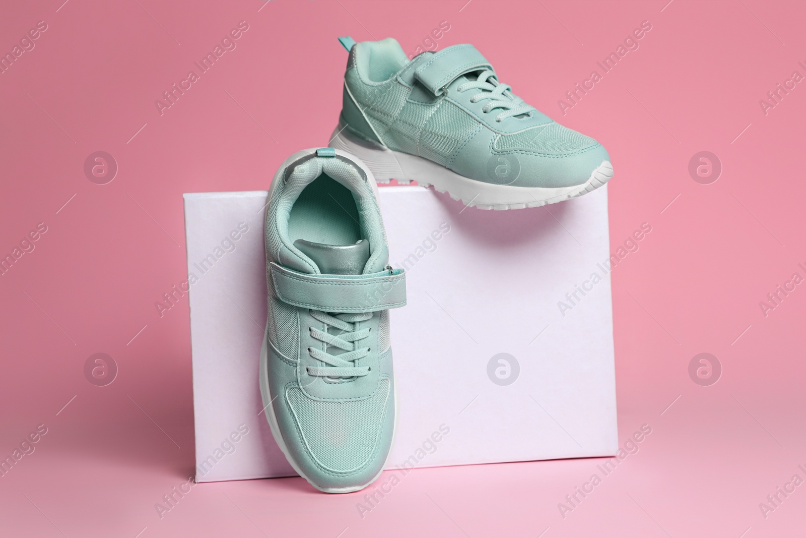 Photo of Pair of stylish sneakers and box on pink background