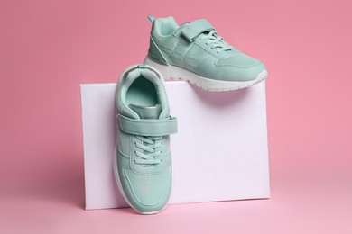 Pair of stylish sneakers and box on pink background