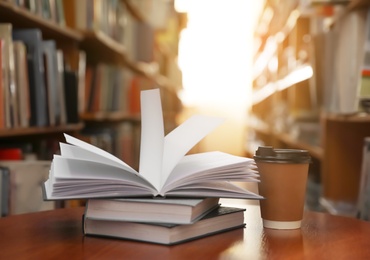 Books and cup of coffee on table in library