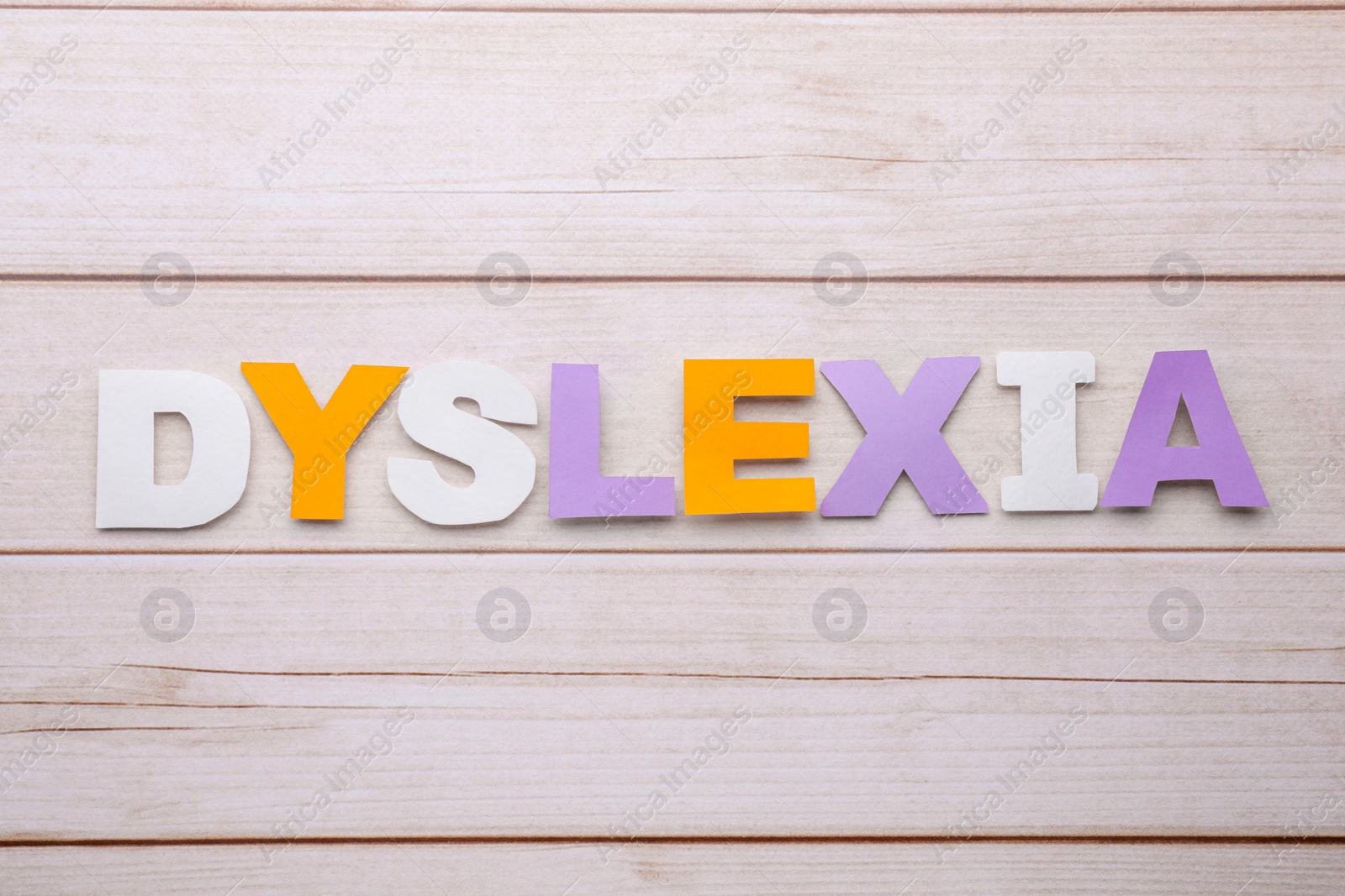 Photo of Word Dyslexia made of paper letters on wooden table, flat lay