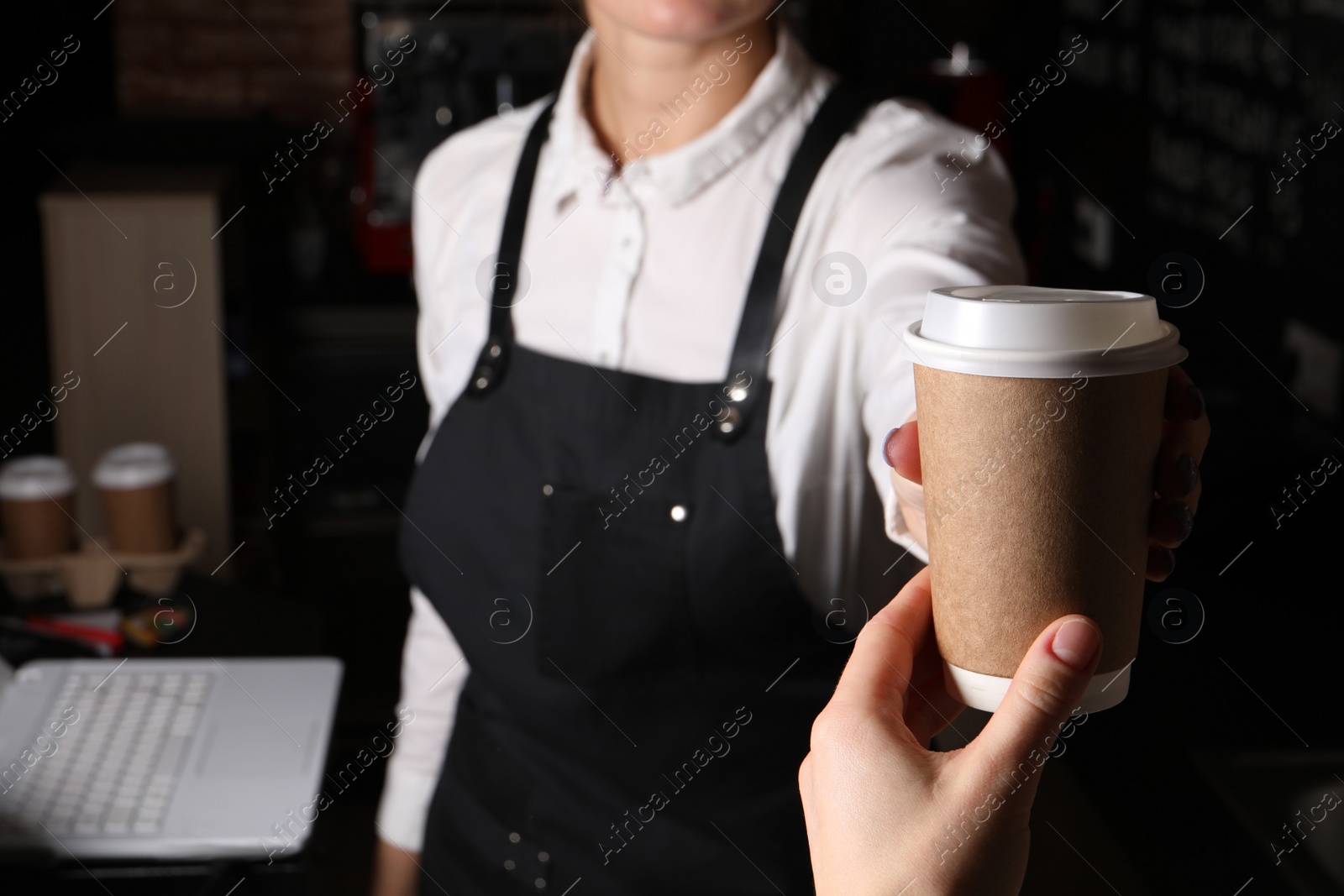 Photo of Barista giving takeaway paper cup with coffee to client in cafe, closeup