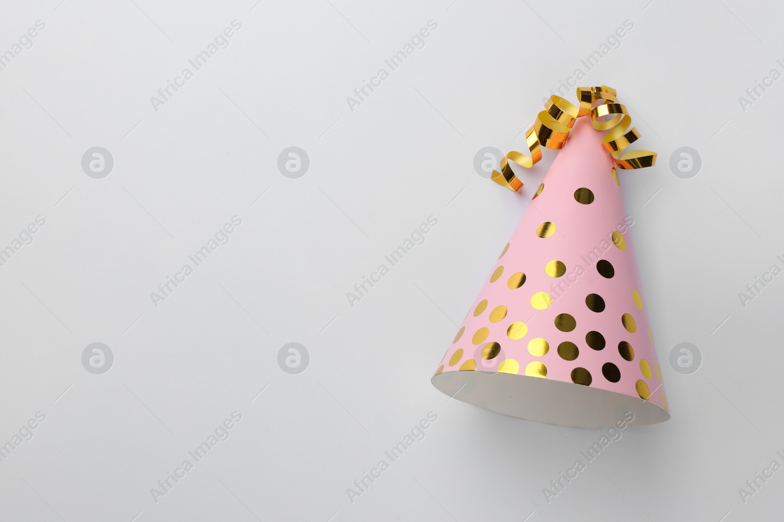 Photo of One pink party hat with serpentine streamers on light background, top view. Space for text