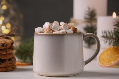 Photo of Cup of hot drink with marshmallows on white table, closeup