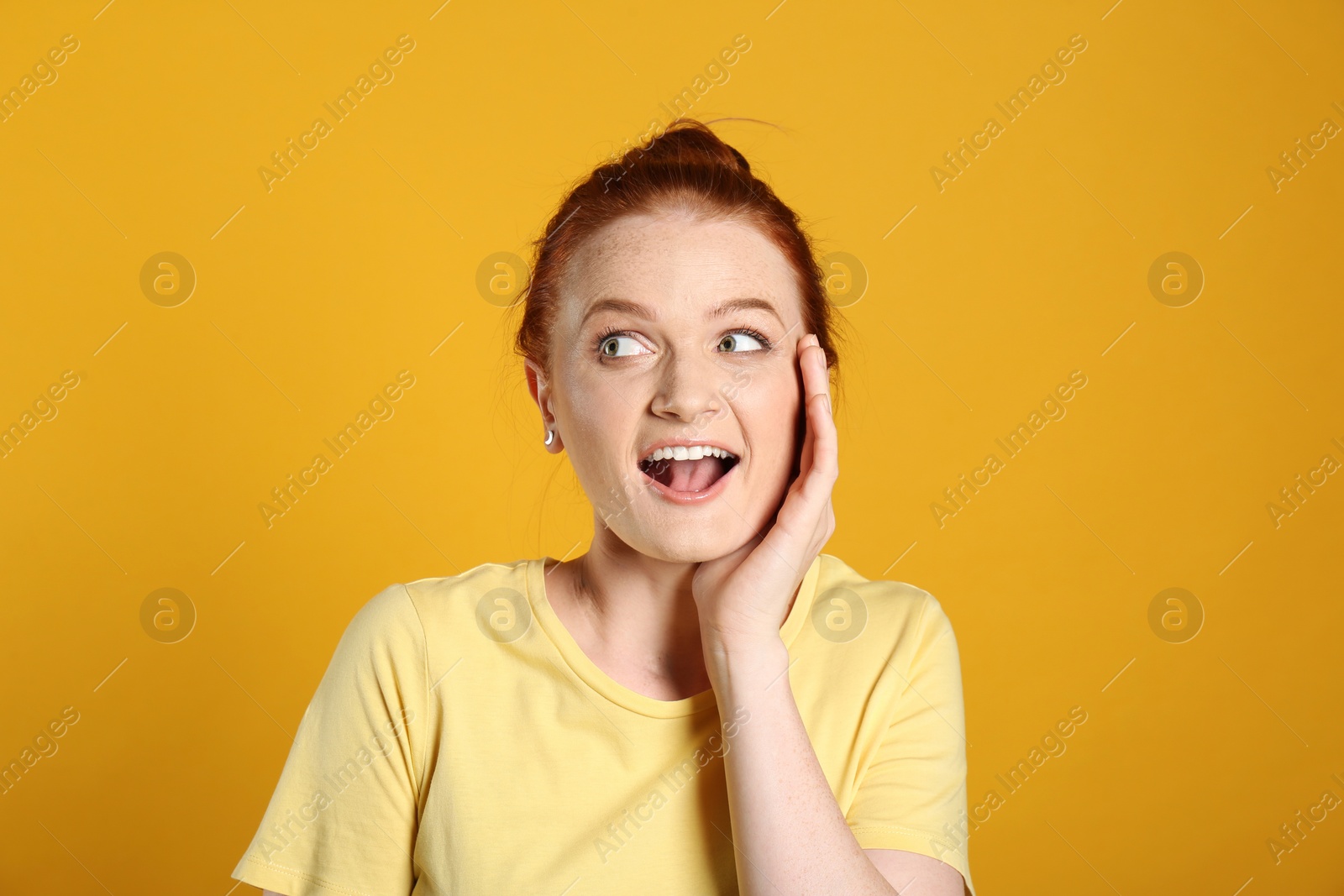 Photo of Portrait of emotional red haired woman on yellow background