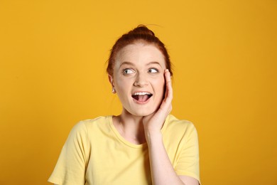 Portrait of emotional red haired woman on yellow background