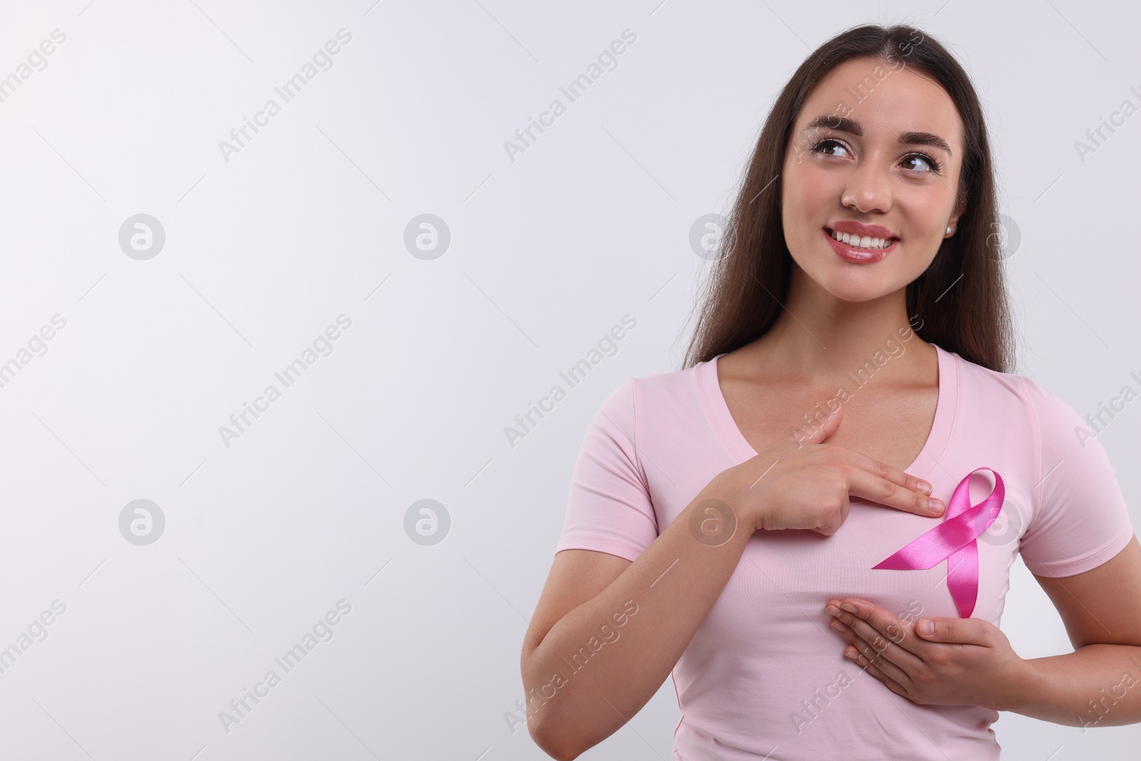 Photo of Beautiful young woman with pink ribbon on white background, space for text. Breast cancer awareness