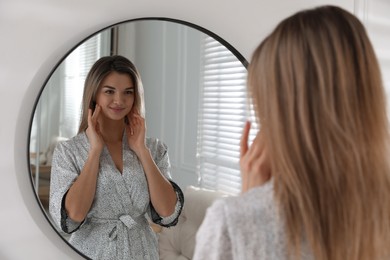Photo of Beautiful young woman near mirror in room