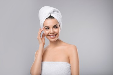 Photo of Happy young woman with towel on head against light grey background. Washing hair