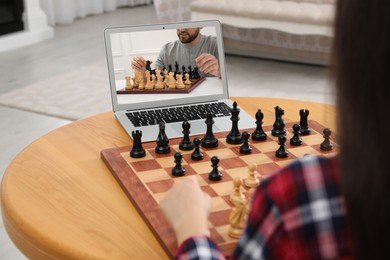 Image of Woman playing chess with partner via online video chat at table indoors, closeup
