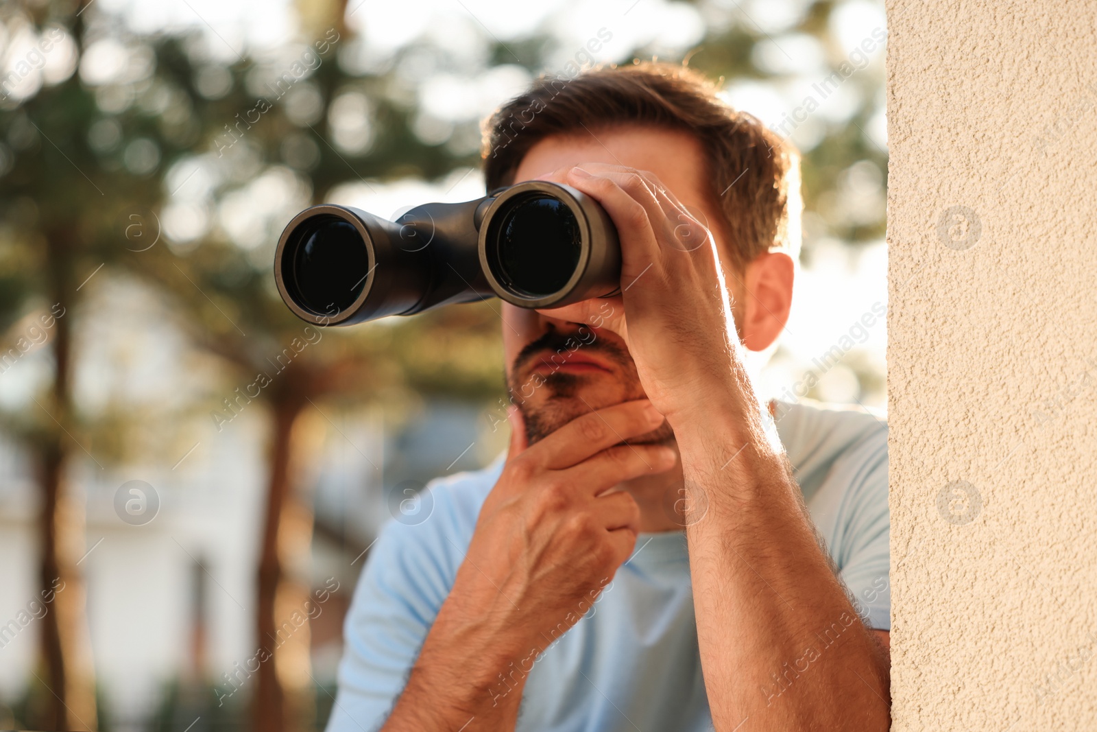 Photo of Concept of private life. Curious man with binoculars spying on neighbours outdoors