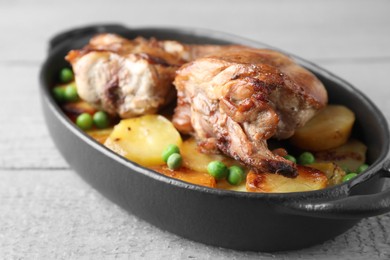 Photo of Tasty cooked rabbit with vegetables in baking dish on grey wooden table, closeup