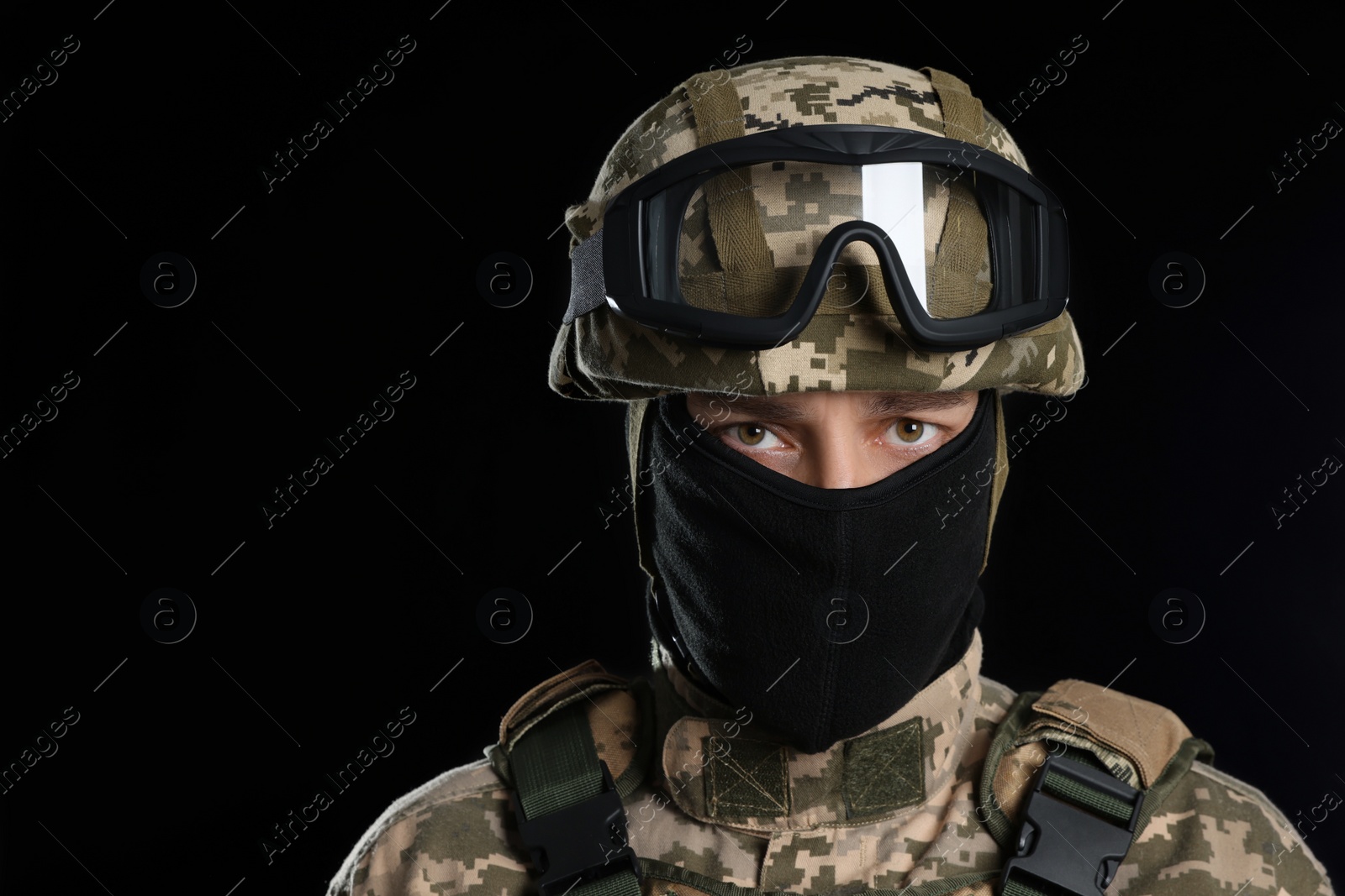 Photo of Soldier in Ukrainian military uniform with tactical goggles and balaclava on black background. Space for text