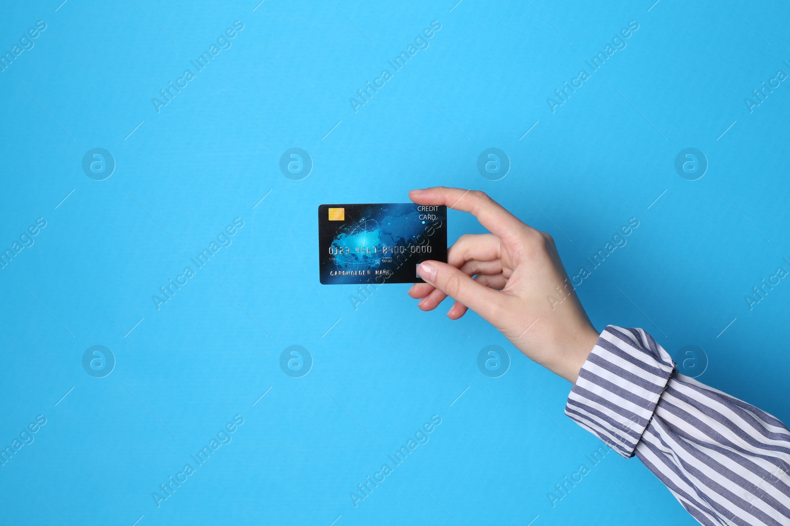 Photo of Woman holding credit card on light blue background, closeup