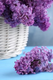 Photo of Beautiful lilac flowers on light blue wooden table, closeup