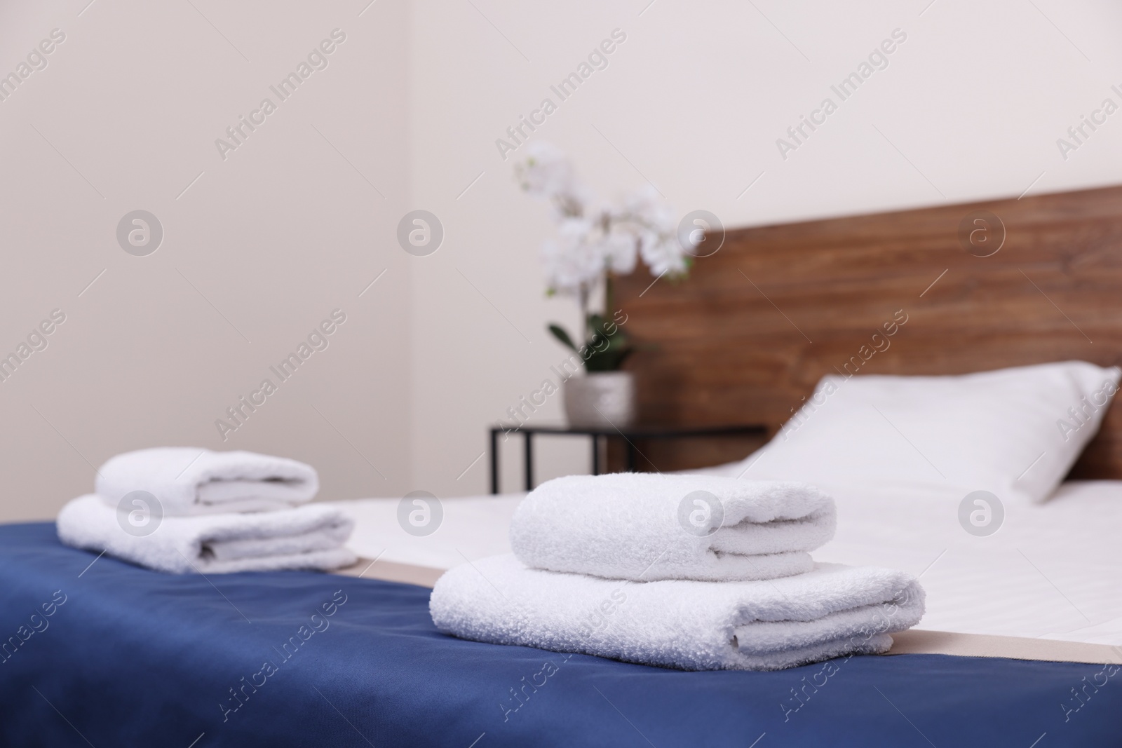 Photo of Clean folded towels on bed in hotel room