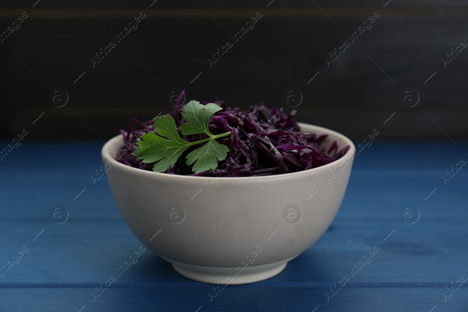 Photo of Tasty red cabbage sauerkraut with parsley on light blue wooden table