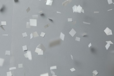 Photo of White confetti falling down on light grey background