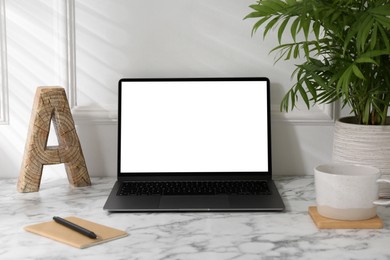 Photo of Office workplace with computer, glasses, cup and stationery on marble table near white wall