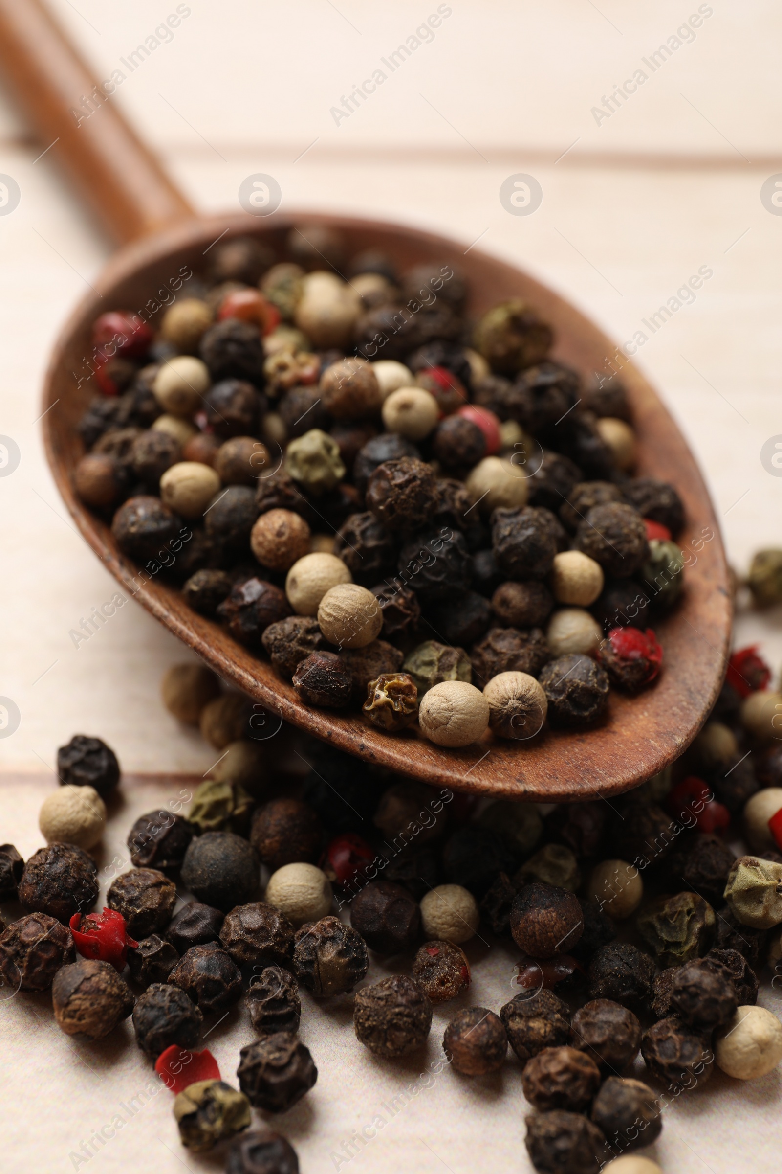 Photo of Aromatic spices. Different peppers in spoon on wooden table, closeup