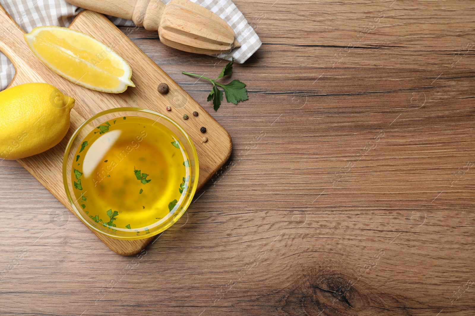 Photo of Bowl of lemon sauce and ingredients on wooden table, flat lay with space for text. Delicious salad dressing