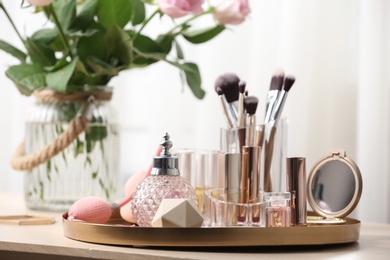 Photo of Tray with different makeup products and accessories on dressing table