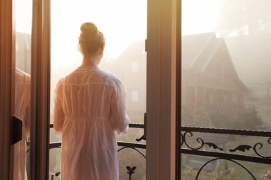 Young woman standing on balcony in early morning