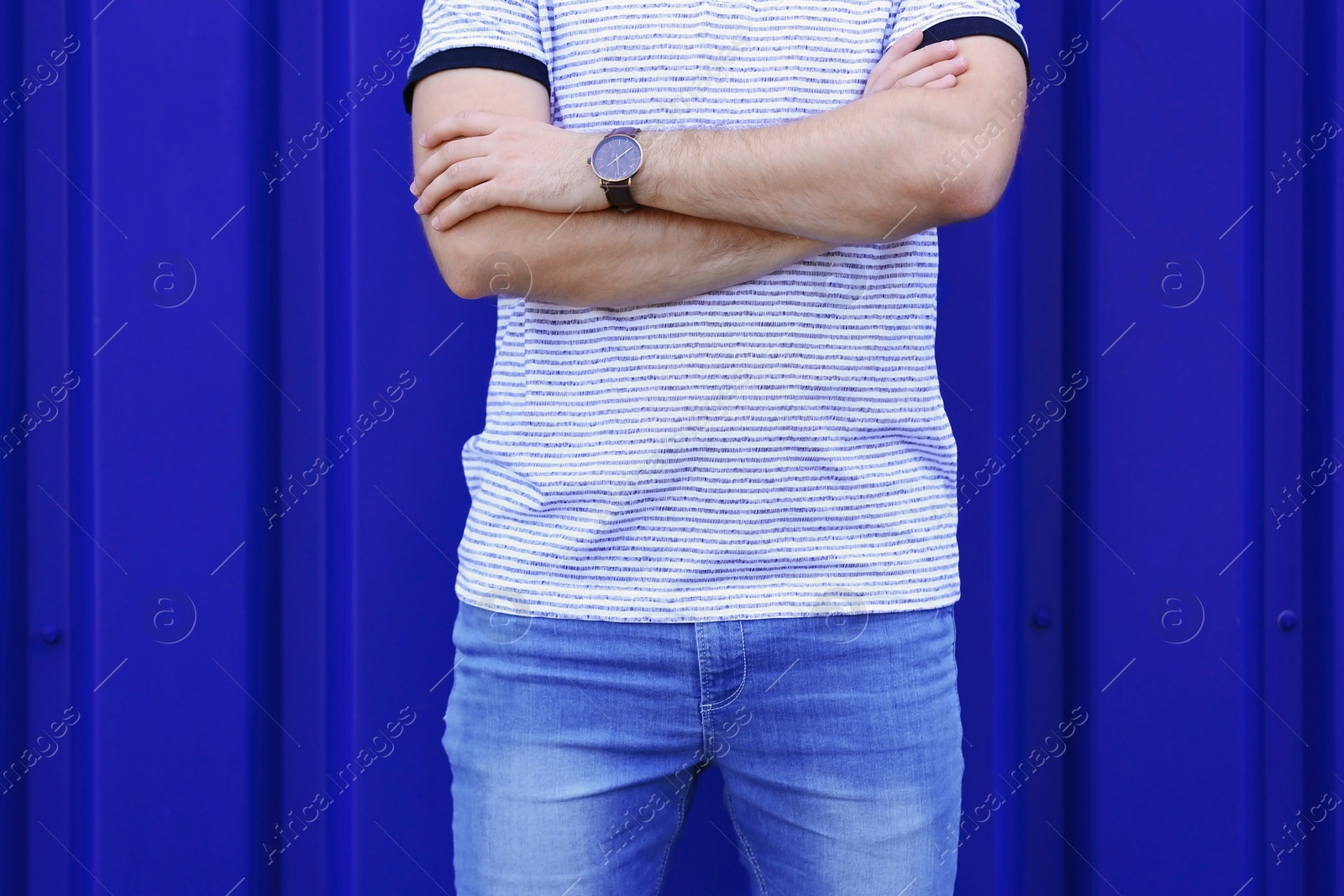 Photo of Young hipster man in stylish jeans posing near color wall