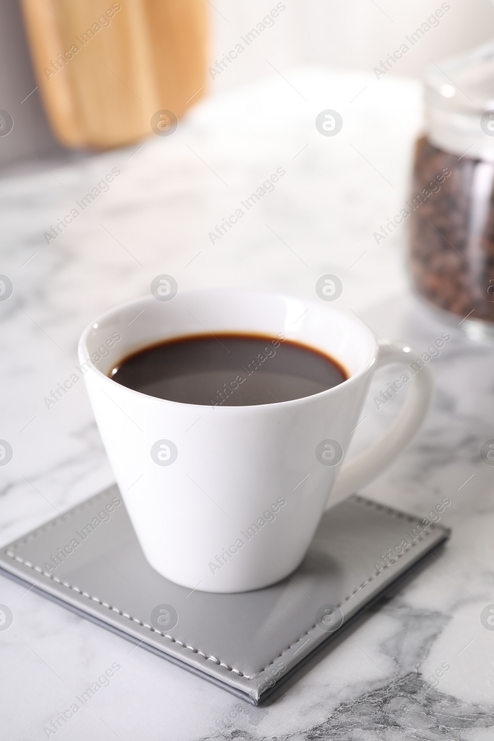 Photo of Delicious coffee in cup on white marble table, closeup