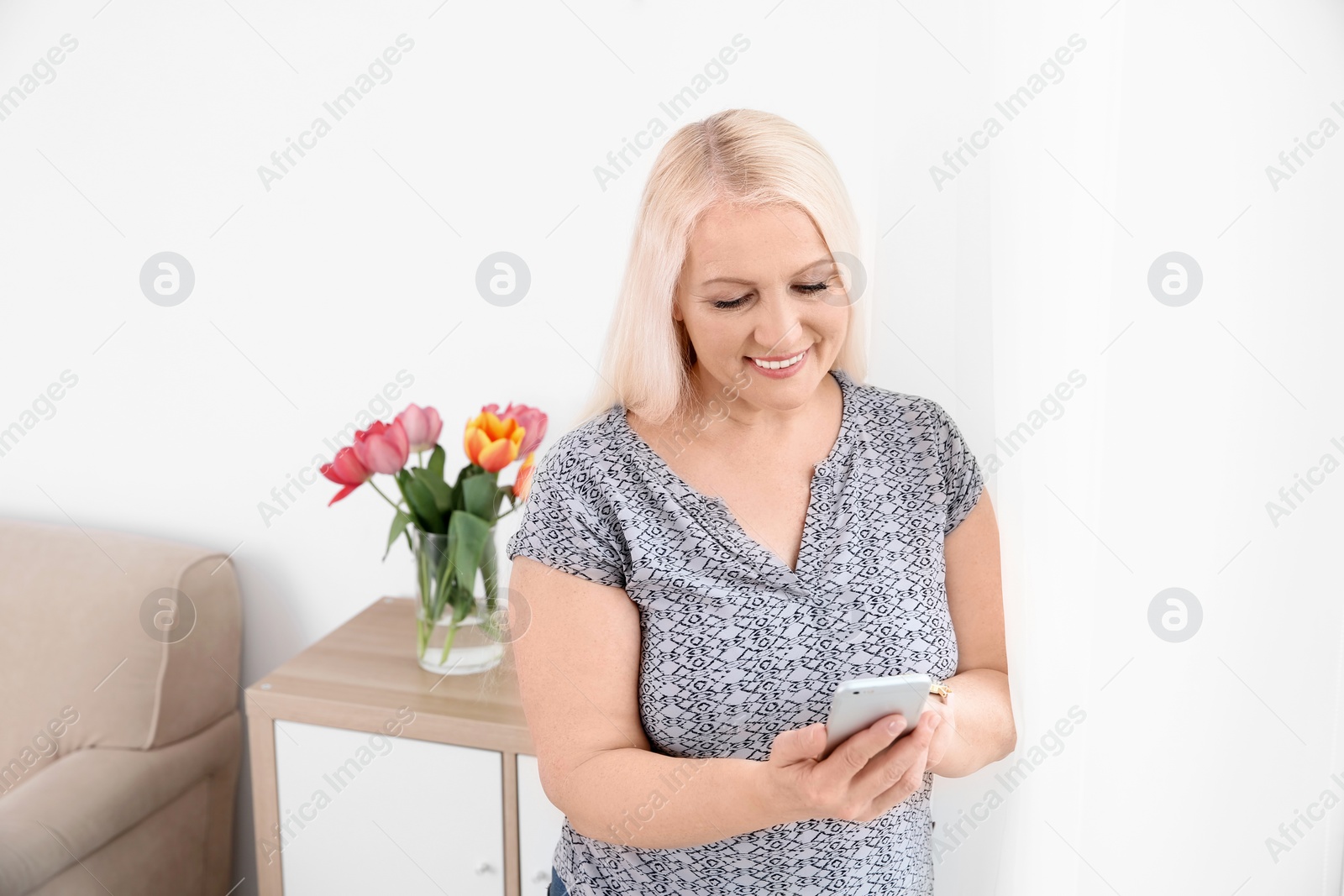 Photo of Mature woman using mobile phone at home