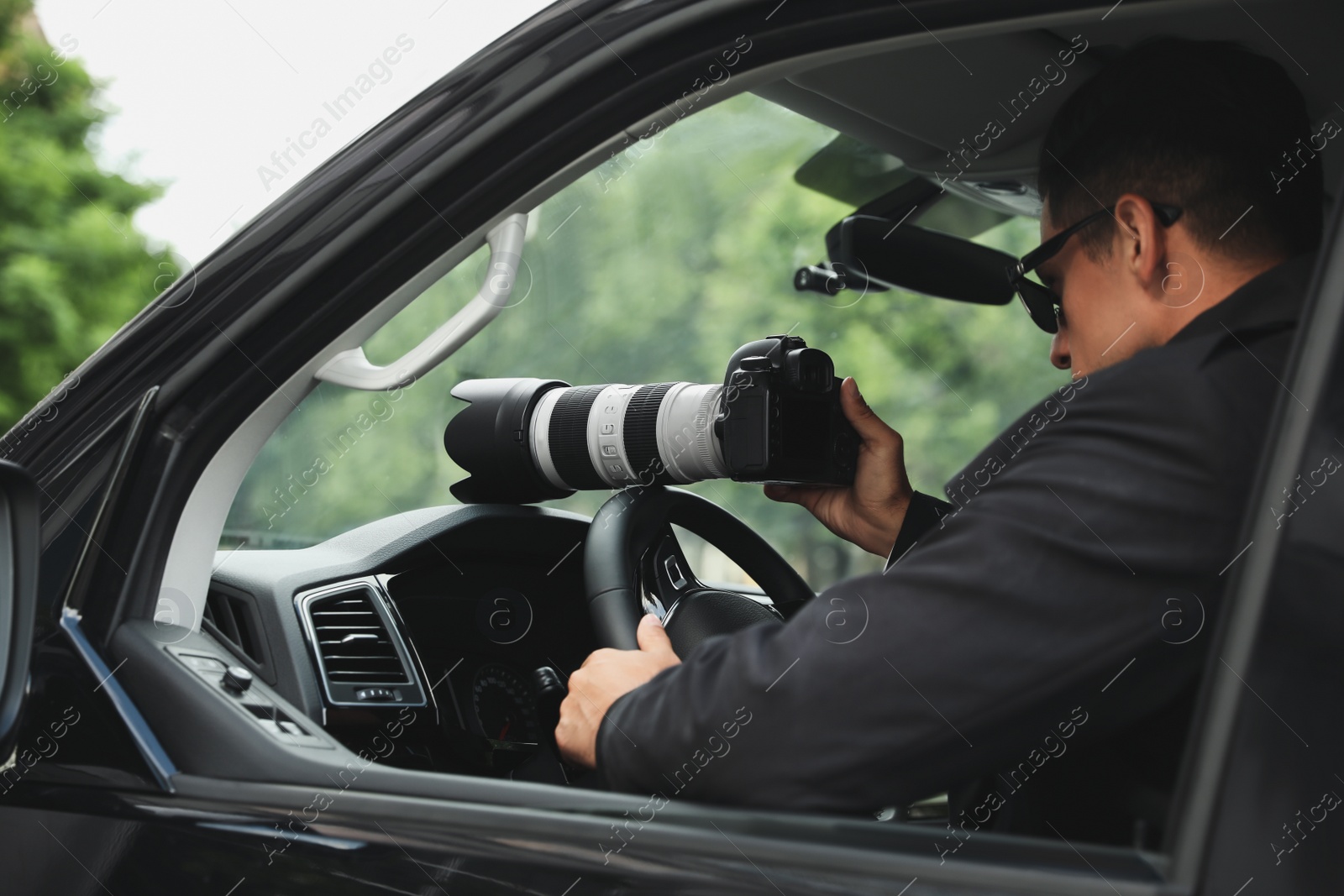 Photo of Private detective with camera spying from car