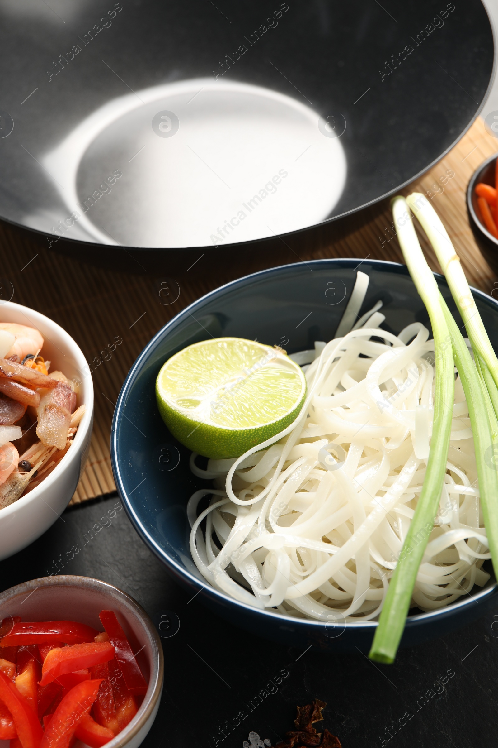 Photo of Black wok and products on dark table, closeup