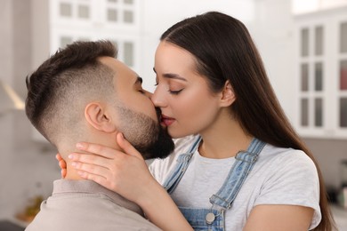 Photo of Affectionate young couple kissing in light kitchen