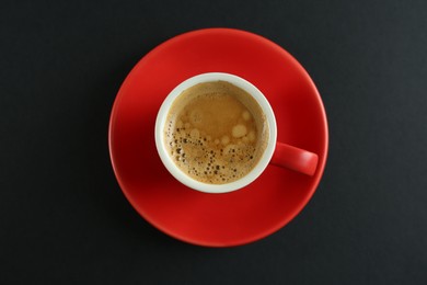 Cup of tasty coffee on black background, top view